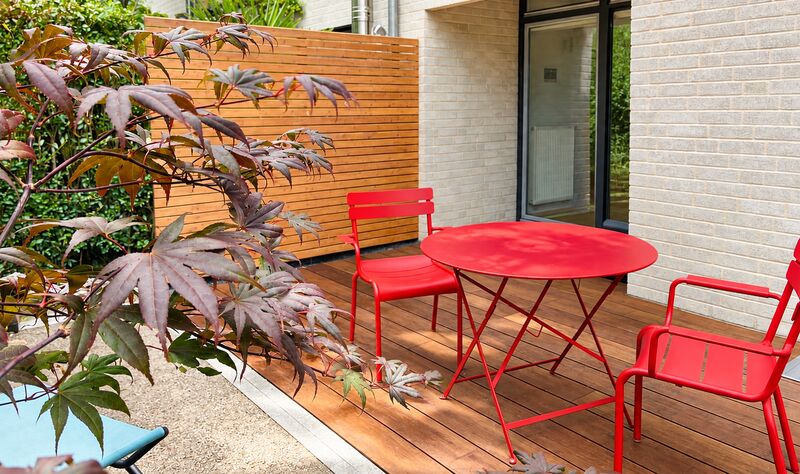 Holzdeck mit Lamellenwand, Ahorn und rotem Bistrotisch